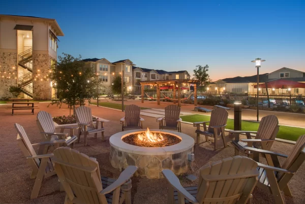 Ten Adirondack chairs around a fire pit in an outdoor lounge area with fairy lights