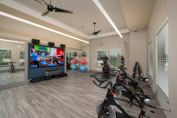 Group fitness room powered by Fitness on Demand with spin bikes, free weights, and other strengthening equipment