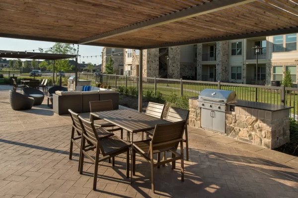 Outdoor grilling station with counterspace under a cabana with ample outdoor furniture for lounging and dining
