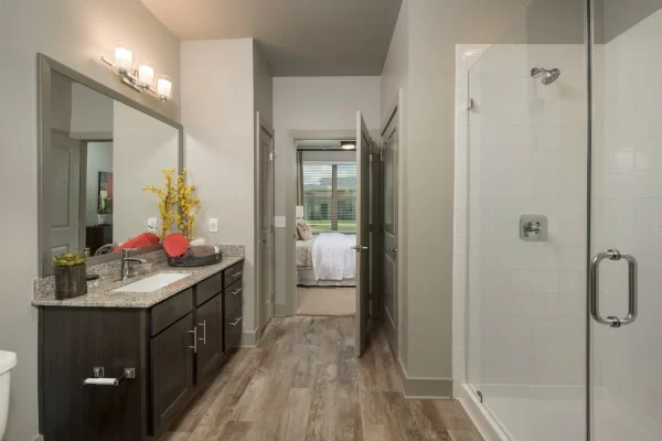 Bathroom with large, granite top vanity, walk-in shower, ample storage, and connected to the bedroom